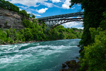 The powerful, churning turquoise rapids of the Niagara River, flowing through a lush green gorge....