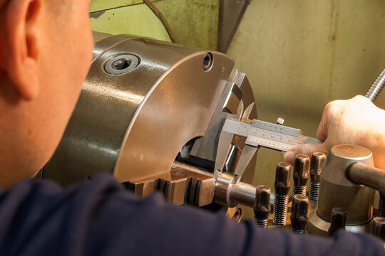 Close up scene the machine operator measuring dimension of metal shaft parts by Vernier caliper. - Powered by Adobe