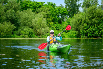 Happy active outdoor lifestyle: adult woman paddling a sea kayak on a pond in the Toronto Islands...