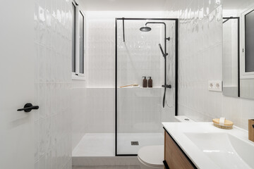 Modern bathroom with a glass shower, white tiles, and wooden accents. Minimalist design featuring a...