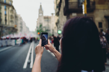 Asian woman photographs street with smartphone, capturing modern urban reality through digital lens and representing autonomy in creative mobile culture.