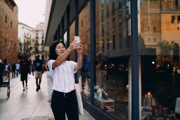 Smiling woman takes selfie on smartphone in bright urban street, highlighting digital empowerment...