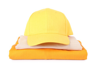 Yellow baseball cap and stack of folded t-shirts isolated on white. Mockup for design