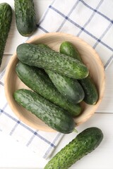 Fresh cucumbers in bowl on white wooden table, flat lay