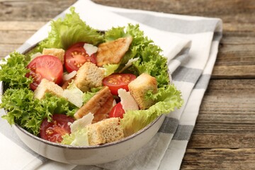 Delicious salad with croutons, chicken, vegetables and cheese on wooden table, closeup