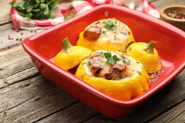 Tasty stuffed pattypan squashes in baking dish on wooden table, closeup