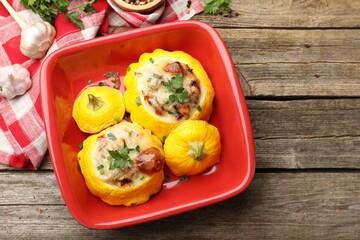 Tasty stuffed pattypan squashes in baking dish on wooden table, flat lay. Space for text