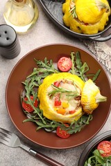Tasty stuffed pattypan squash with tomatoes and arugula served on grey table, flat lay