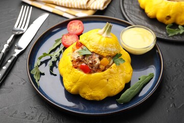 Tasty stuffed pattypan squash with sauce served on black table, closeup