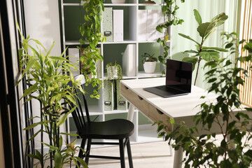 Biophilic interior design. Stylish workplace with laptop and houseplants in office