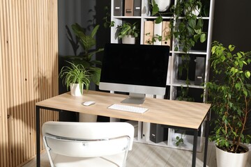 Stylish workplace with modern computer and floral decor in office. Biophilic interior design