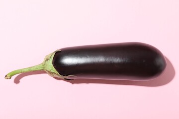Ripe eggplant on light pink background, top view