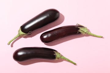 Ripe eggplants on light pink background, flat lay