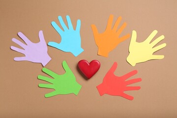 Tolerance concept. Colorful paper hands and heart on brown background, flat lay