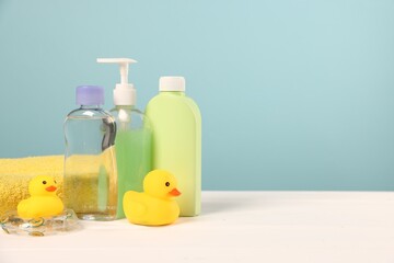 Baby accessories and bathing products on white wooden table against light blue background, space for text