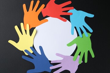 Fototapeta premium Tolerance concept. Colorful paper hands and empty card on black background, flat lay. Space for text