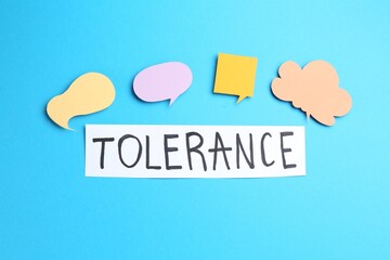 Card with word Tolerance and speech bubbles on light blue background, flat lay