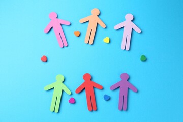 Tolerance concept. Colorful human figures and hearts on light blue background, flat lay