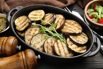 Grilled slices of eggplant with microgreens served on wooden table, closeup