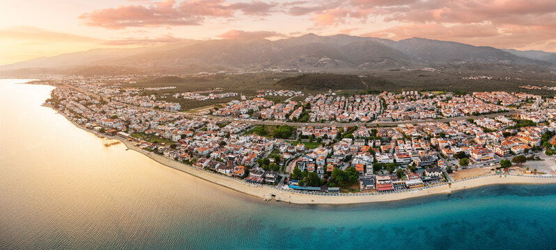 Calm sea reflecting the warm colors of sunset over the coastal town of Akcay, Turkey, with mountains in the background