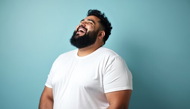 Joyful Hispanic man with plus size body positive figure laughs heartily in studio portrait. He wears white casual t-shirt against colorful background. Confident, happy, smiling male model in his 30s. - Powered by Adobe