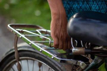 Hand holding the rack of a bicycle seat on a sunny day