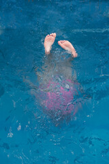 summer swimming in the pool. silhouette of a girl underwater, only heels are on the surface of the water