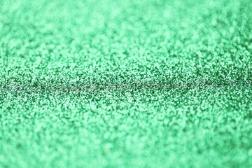 Beautiful green glitter sparks texture as background with shallow depth of field