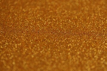 Beautiful golden glitter sparks texture as background with shallow depth of field