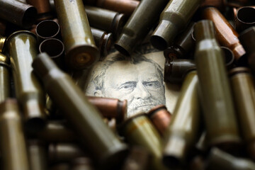 Conceptual image of US presidents face surrounded by many used rifle cartridges. Details of US...
