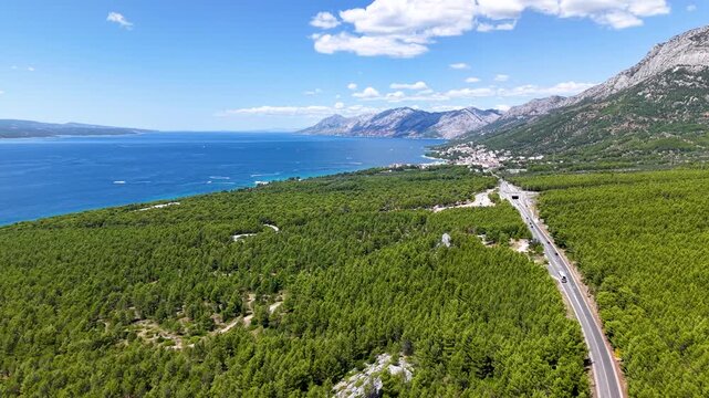 Drone panorama of Baska Voda coast with Biokovo mountains pine forest Adriatic highway and deep blue sea