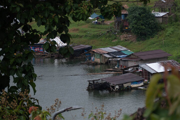 The Mon village in Kanchanaburi with morning mist on the green mountains and clear river.
