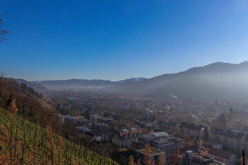 Panoramic view of the foggy city of Freiburg with snow-capped mountain peaks in the background on a winter day 