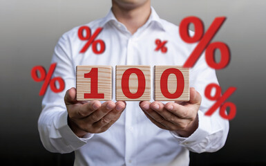 Businessman holding wooden blocks with 100 percent, symbolizing maximum commitment, a full guarantee, or high interest rates.