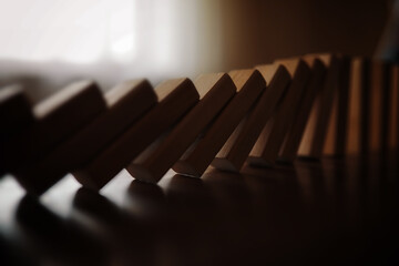 domino effect concept with wooden tiles blocked by hourglass with background