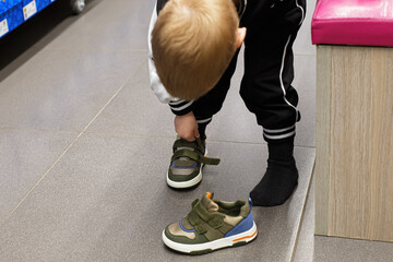 A child tries on sneakers in a shoe store. Retail trade.