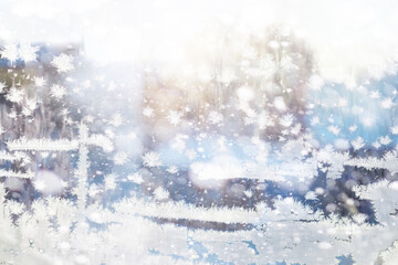 Winter landscape through a frozen window. Blurred snow background. Trees and plants covered with...