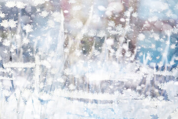 Winter landscape through a frozen window. Blurred snow background. Trees and plants covered with...