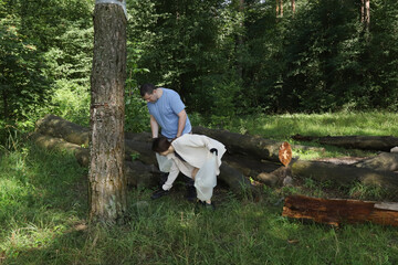 Dad and daughter volunteering to clean forest clearing, picking up litter and protecting nature,...