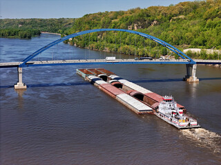 Aerial view of a large barge traveling under the Dale Gardner Veterans Memorial Bridge at Savanna illinois on the Mississippi River