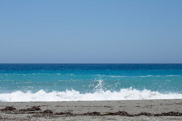Turquoise sea waves crashing on sandy beach on sunny day