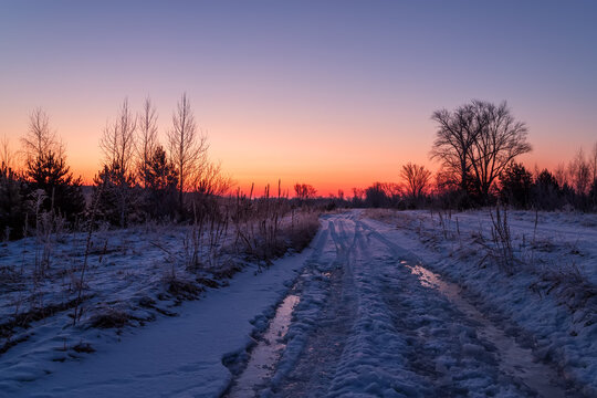 The road in the winter field at sunrise. Winter landscape with road and beautiful sky in the morning