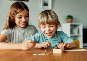 Portret of brother and sister having fun together playing board game pick-up sticks at home