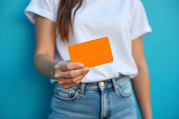 woman holding orange card, blue background, denim jeans, close up, dynamic composition,natural lighting, detailed texture,soft