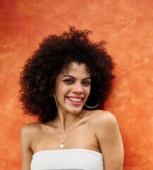 A portrait of young happy latina woman posing by  a colorful wall in the street outdoors