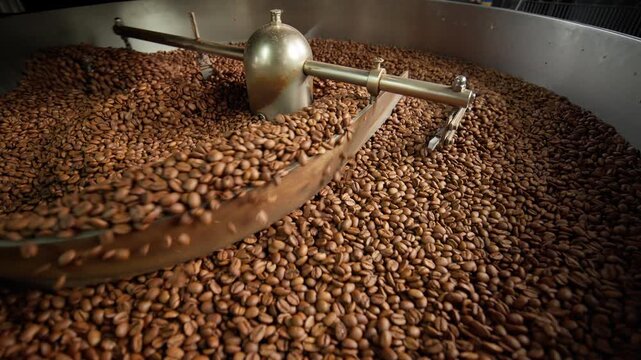 Fresh roasted coffee beans cooling in large industrial mixer machine roaster blend at modern factory aromatic brown grains blending mixing cocoa roasting closeup view of equipment production process