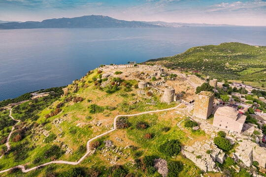 Aerial view of Assos ancient city with its Temple of Athena ruins on the hilltop overlooking Edremit Gulf at sunset, Behramkale, Canakkale, Turkey
