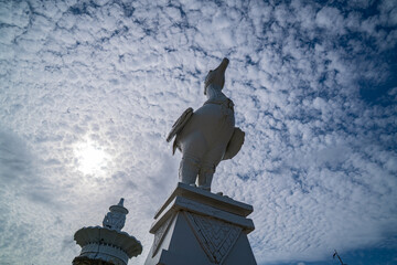 The sculpture at the Karon Beach roundabout in Phuket stands beneath a sky filled with small,...