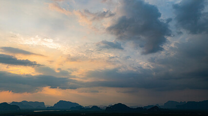 Spectacular sunrise aerial view of Phang Nga's limestone mountains silhouetted against pink and golden clouds. The tropical mangrove forest stretches below, painting a vivid natural landscape.
