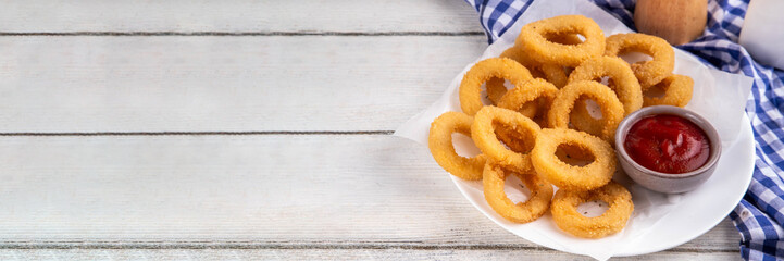 Golden onion rings with ketchup sauce, airfryer cooked tasty onion ring snacks on white wooden table copy space